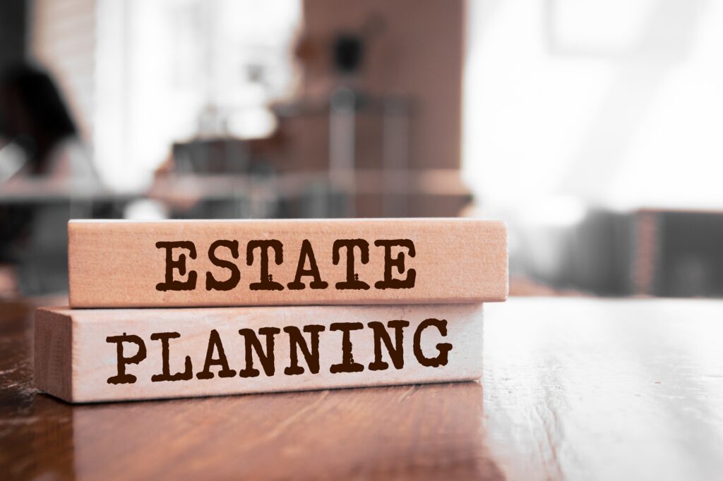 Two wooden blocks with the words "estate planning" written on them sit on a wooden table in a house.