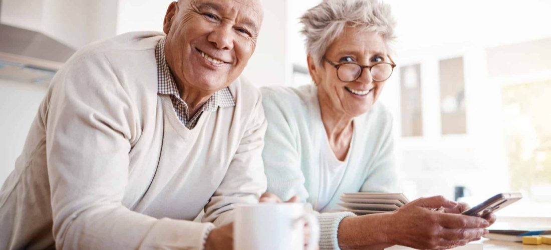Portrait, senior and old interracial couple relax in home kitchen in the morning with coffee happy, smile and confident together. Old man and elderly woman on counter enjoying retirement in happiness.