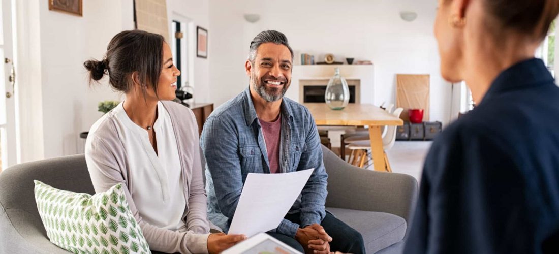 Happy mature couple discussing investments with financial broker during meeting at home. Happy middle eastern man and hispanic woman discussing about financial planning with consultant at home. Financial consultant presenting new investment plan to smiling mature couple at home.